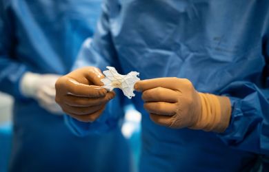 Zwei Hände in Handschuhen halten eine neue Pulmonalklappe während eines Kathetereingriffs.