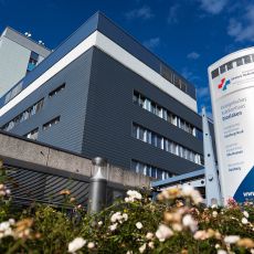Weg zum Haupteingang des Evangelischen Krankenhauses Dinslaken mit Schild des Krankenhauses, auf dem auch das Logo und der Name des Klinikverbundes zu sehen sind.