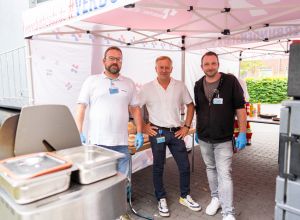 Gruppenfoto unter dem Pavillon bei der Grillaktion: Lars Oppers und Hagen Fleischmann von der örtlichen Pflegedienstleitung sowie Marc-André Dost, pflegerischer Leiter der Zentralen Notaufnahme, stehen nebeneinander. Sie haben die Aktion durchgeführt.