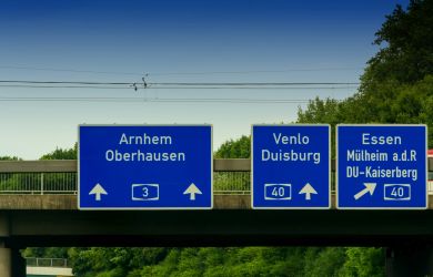 Drei blaue Autobahnschilder mit weißen Richtungspfeilen hängen an einer Brücke. Auf einem steht „3 Arnhem Oberhausen“, die anderen verweisen auf die A40 Venlo Duisburg und A40 Essen, Mülheim an der Ruhr und DU-Kaiserberg.