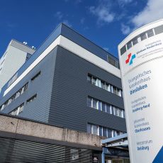 Beschilderung vor dem Haupteingang des Evangelischen Krankenhauses Dinslaken mit dem Namen des Krankenhauses, dem Logo des Klinikverbundes und dem Namen des Verbunds.