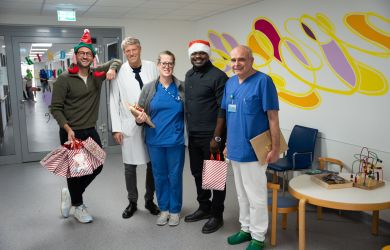 Weihnachtlicher Besuch von Gerald Asamoah auf der Station der Kinderkardiologie. Gruppenbild mit Gerald Asamoah und Ärzten des Kinderherzzentrums auf dem Krankenhausflur.