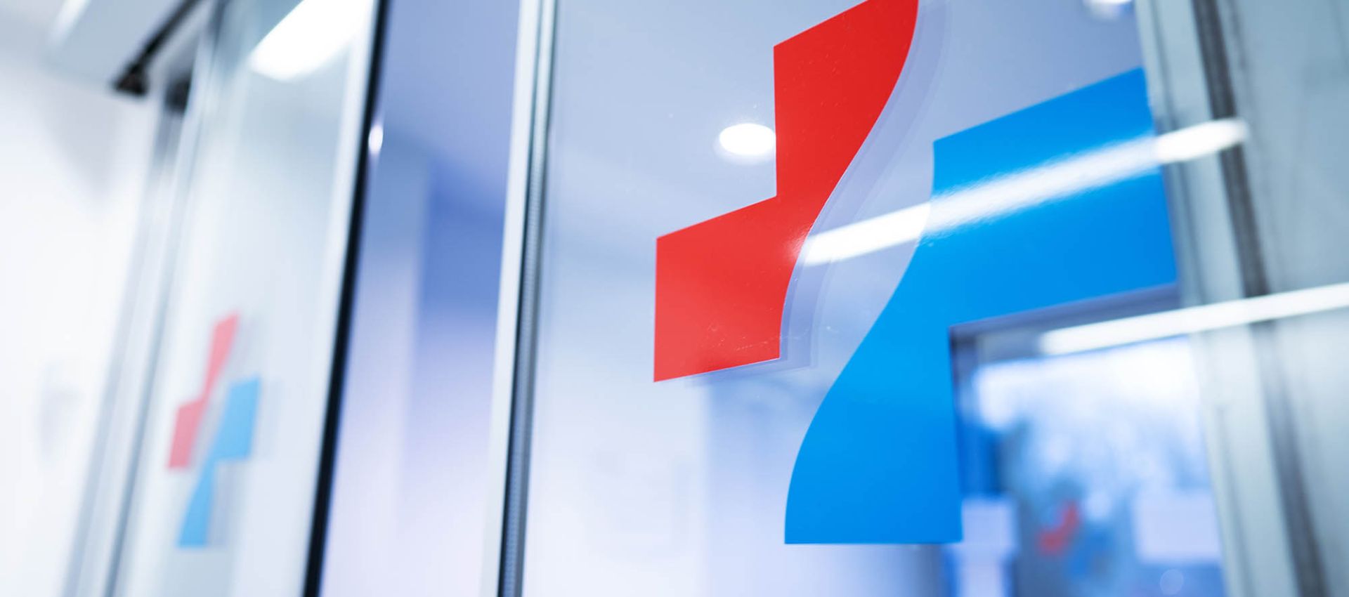Leicht geöffnete Glas-Durchgangstür mit dem Logo des Klinikverbundes.