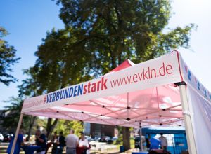 Weißer Pavillon mit blau-rotem Schriftzug "verbunden stark" auf einer Wiese