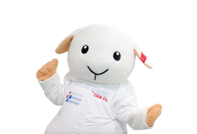 Portrait des Klinik-Maskottchens EVA im Schafkostüm mit weißem Shirt und rotem Verband am Ohr