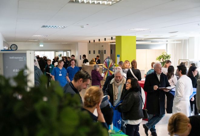 Zahlreiche Besucherinnen und Besucher informieren sich beim Tag der Orthopädie im Evangelischen Krankenhaus Dinslaken. In einem hellen Veranstaltungsbereich führen Gäste, Ärzte und Pflegekräfte Gespräche; im Hintergrund steht ein buntes Glücksrad.
