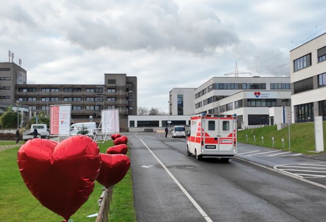 Blick auf die Einfahrt zum Krankenhaus. Am Zaun links sind große, rote Herzballons befestigt. Rechts steht ein RTW. Im Hintergrund ist das Klinikgebäude zu sehen.