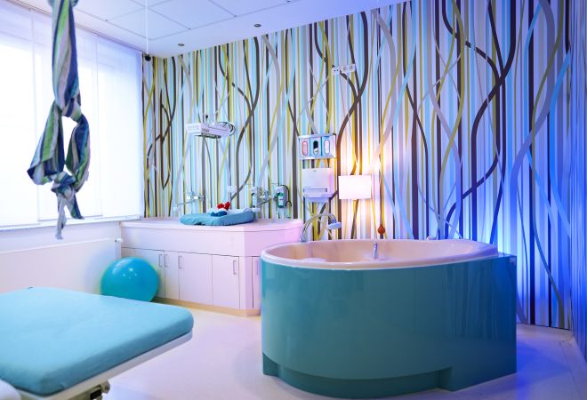 Heller, freundlich gestalteter Kreißsaal mit einer hellblauen Geburtswanne.