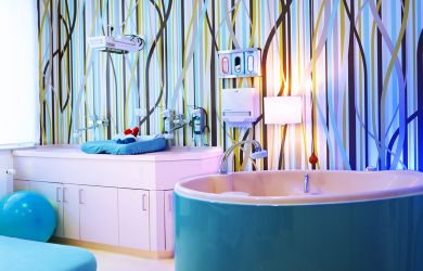 Heller, freundlich gestalteter Kreißsaal mit einer hellblauen Geburtswanne.