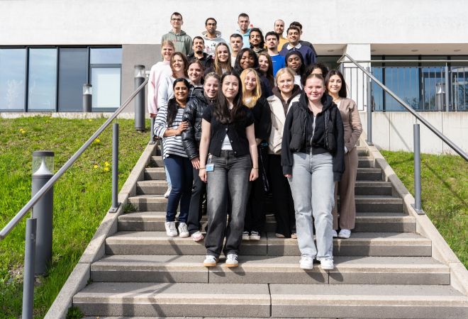 Gruppenfoto mit 22 Auszubildenden und einer Lehrerin. Die Gruppe steht auf der Treppe vor dem Verwaltungsgebäude des Evangelischen Krankenhauses Duisburg-Nord.