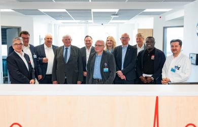 Gruppenfoto auf der Kinderintensivstation: NRW-Gesundheitsminister Karl-Josef Laumann mit den Geschäftsführern des Klinikverbunds EVKLN, Oberbürgermeister Sören Link, Duisburger Politiker:innen, Medizinern sowie Ex-Profi-Fußballer Gerald Asamoah.
