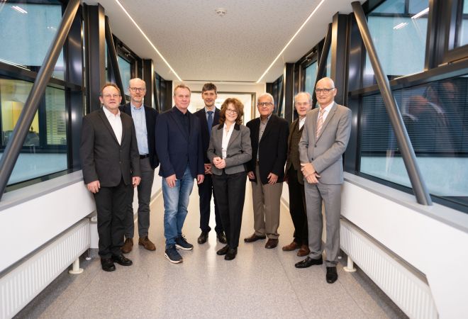 Gruppenbild des Aufsichtsrats des Evangelischen Klinikums Niederrhein, aufgenommen im Übergang zwischen zwei Gebäudeteilen mit Fensterfronten.