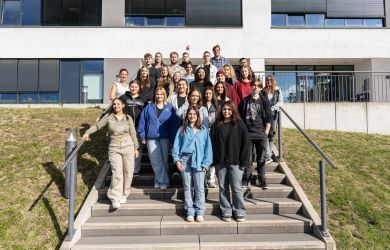 Gruppenfoto mit 26 Auszubildenden und einem Lehrer. Die Gruppe steht auf der Treppe vor dem Verwaltungsgebäude des Evangelischen Krankenhauses Duisburg-Nord.