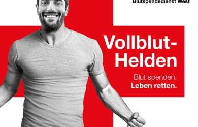 Werbeplakat des DRK-Blutspendedienstes West mit rotem Hintergrund, Rotkreuz-Logo und dem Slogan „Vollblut-Helden – Blut spenden. Leben retten.“ Ein Mann steht mit ausgestreckten Armen im Zentrum.