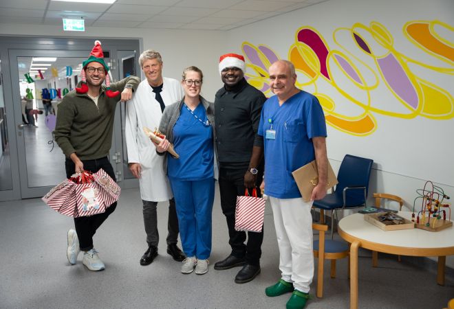 Weihnachtlicher Besuch von Gerald Asamoah auf der Station der Kinderkardiologie. Gruppenbild mit Gerald Asamoah und Ärzten des Kinderherzzentrums auf dem Krankenhausflur.