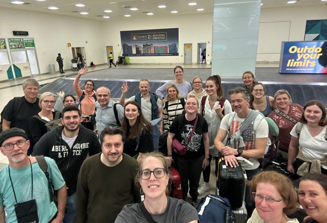 Das Team des Herzzentrums Duisburg ist sicher am Flughafen Accra gelandet und wartet mit Koffern und Taschen am Gepäckband, bevor es weitergeht. Die Gruppe macht ein Selfie.