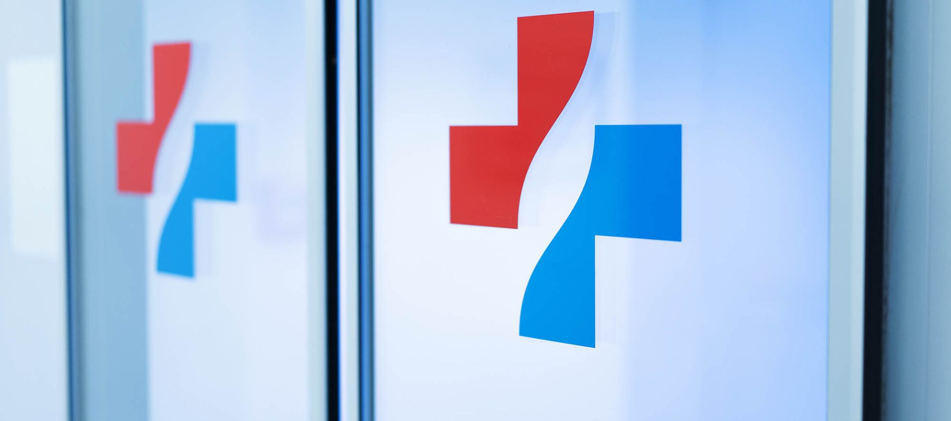 Glas-Durchgangstür mit dem Logo des Klinikverbundes in der Mitte der Scheibe.