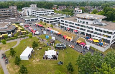 Vogelperspektive auf das Klinikgelände während des Tags der offenen Tür: Im Bild das Krankenhaus- und Verwaltungsgebäude, davor eine Wiese mit Pavillons, Info- und Aktionsständen sowie Gastronomiewagen, umgeben von Besucherinnen und Besuchern.