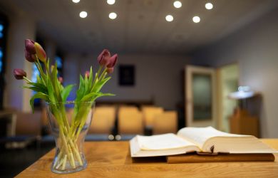 Blick vom Altar eines kleinen Andachtsraums im Evangelischen Krankenhaus Dinslaken. Auf dem Altar liegen ein Buch und eine Vase mit violetten Tulpen.